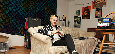 A teenager sitting on a couch on his phone